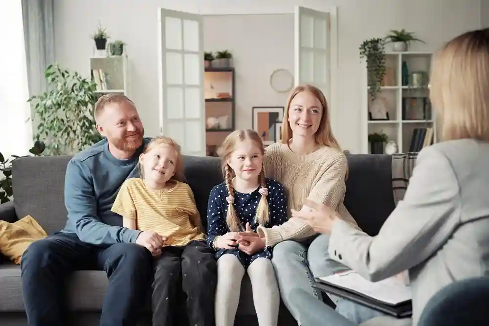 A therapist speaks with a family of four, including two young daughters, during family therapy