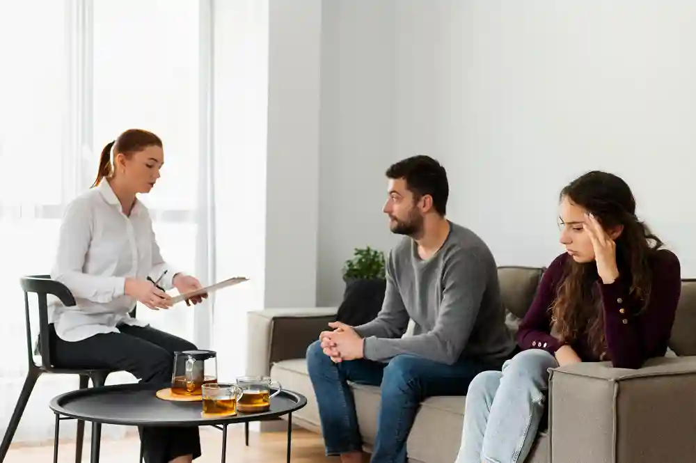 A couple sits on a lavender sofa during an in-person therapy session in Tampa, FL