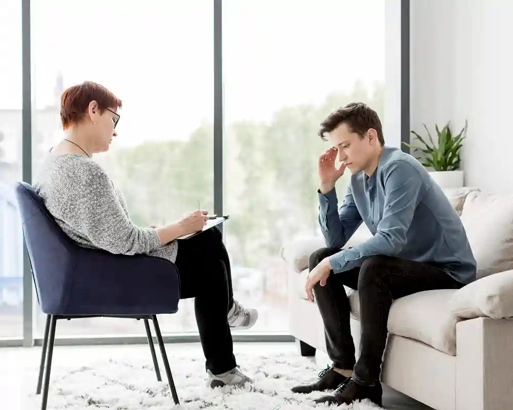 An adult male sits on a white sofa during an individual therapy session in Tampa, FL