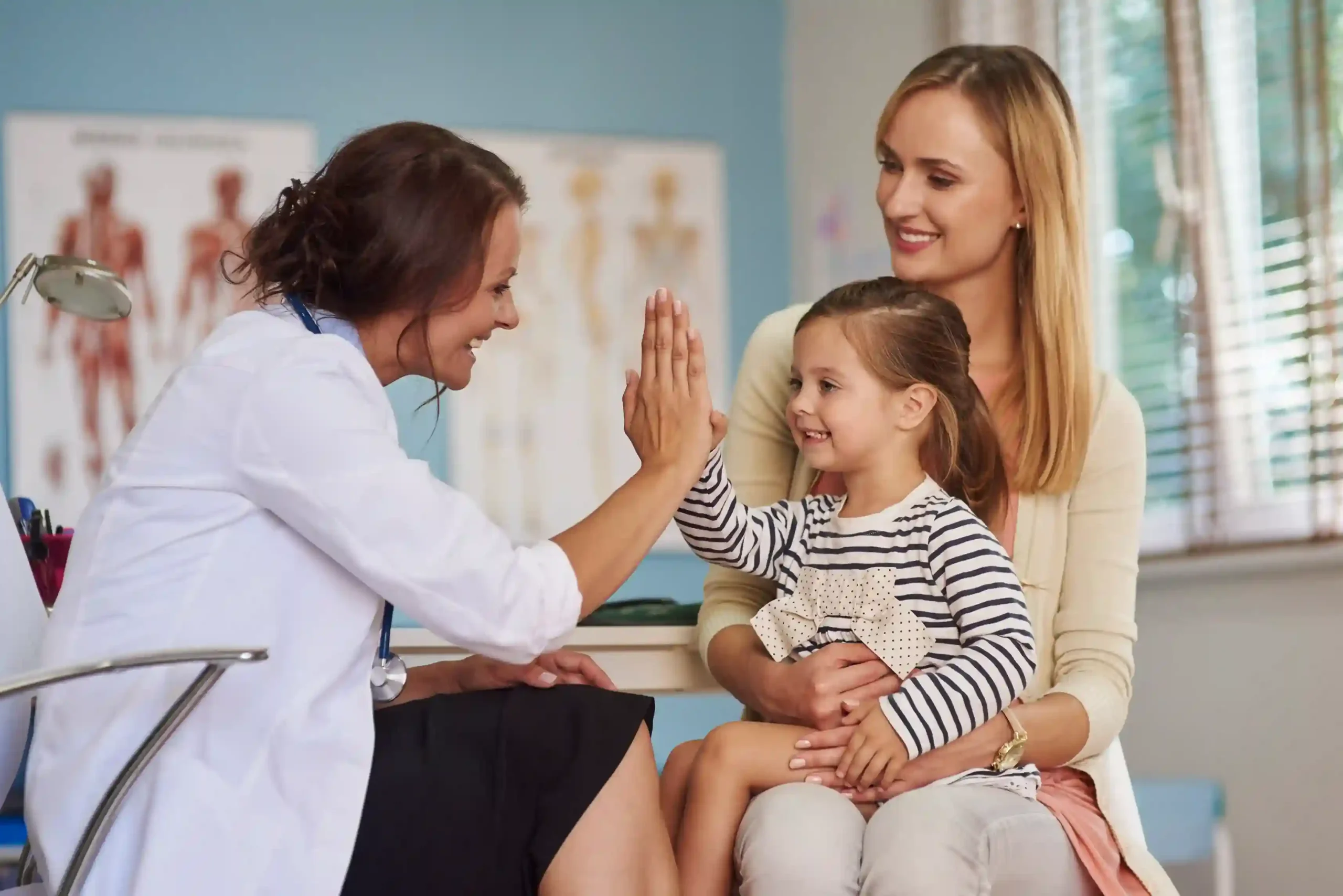 Doctor giving a high five to a child during a family wellness appointment.