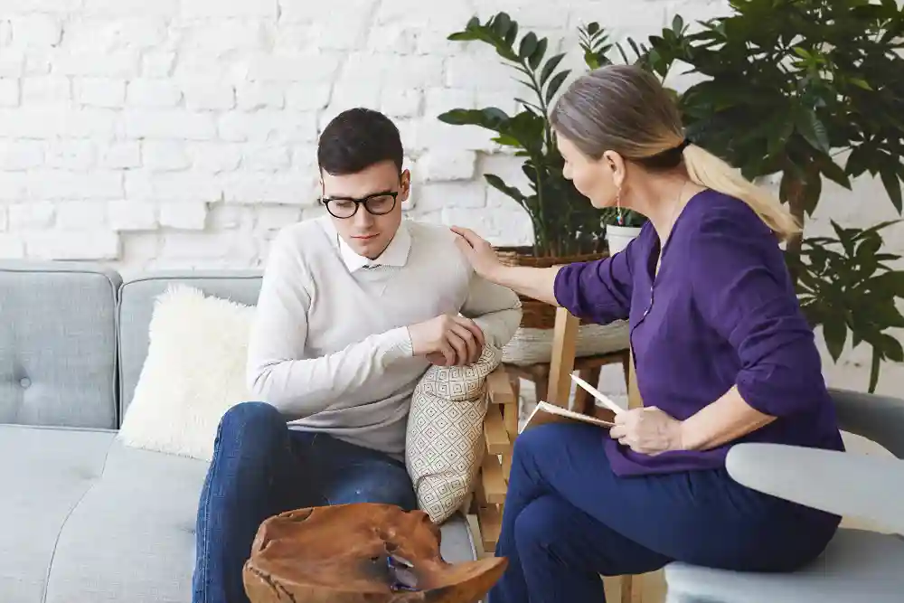 Female therapist offers a supportive gesture to a young man during a teen and adult therapy session